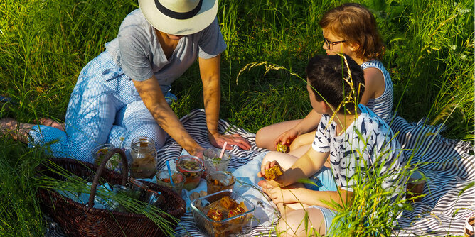 Gemeinsames Picknicken | © SONNENTOR Auf dem Foto sieht man eine Familie beim Picknicken auf einer Wiese. | © SONNENTOR
