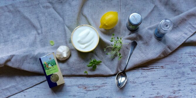 Dips | © SONNENTOR Auf dem Foto sieht man eine Schale mit Dip. Daneben sind Knoblauch, Kräuter, Zitronen und Gewürze zu sehen. | © SONNENTOR