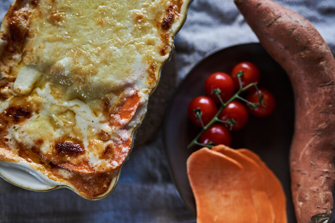 glutenfreie Lasagne | © SONNENTOR Auf dem Foto ist glutenfrei Lasagne aus Süßkartoffeln zu sehen. Daneben sieht man Tomaten und Süßkartoffelscheiben. | © SONNENTOR