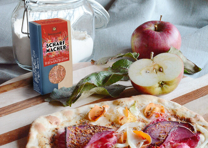 Rote Rüben Focaccia | © SONNENTOR Auf dem Foto sieht man Foccacia mit Roten Rüben. Daneben sieht man Äpfel und auch die SONNENTOR Scharfmacher Gewürzblüten. | © SONNENTOR